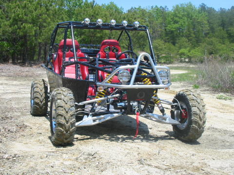 Rugged off-road vehicle with red body and black frame on metal fabrication background.