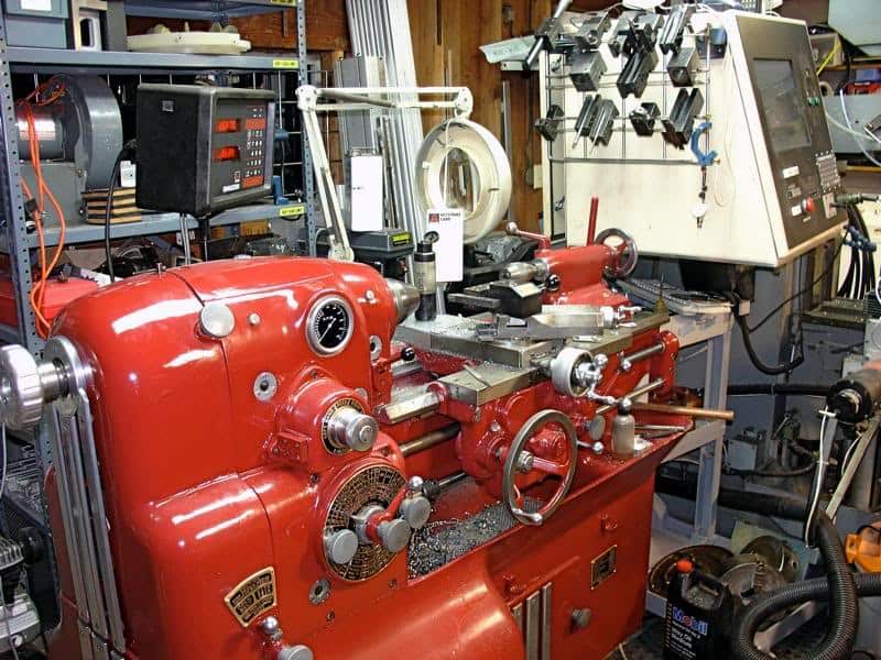 Large red lathe with various tools and equipment in a workshop setting.