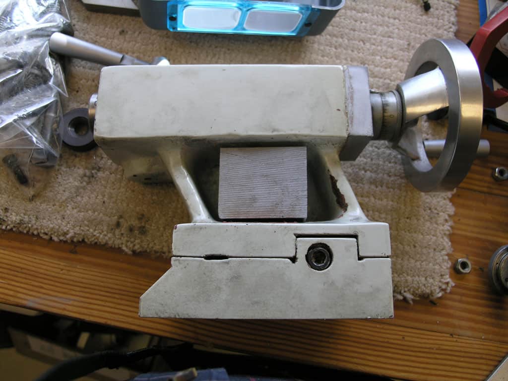 Heavy-duty metalworking vise with sturdy base and adjustable jaws on a wooden workbench.