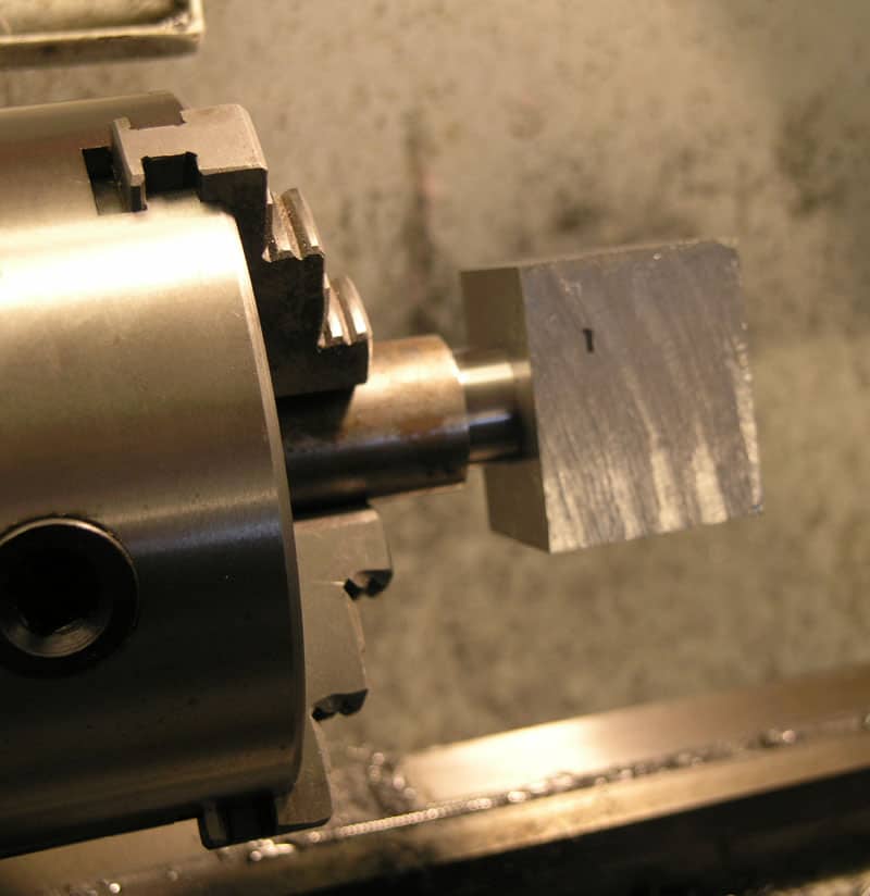 Close-up view of a lathe's tailstock with metal part bearing the numeral "1".