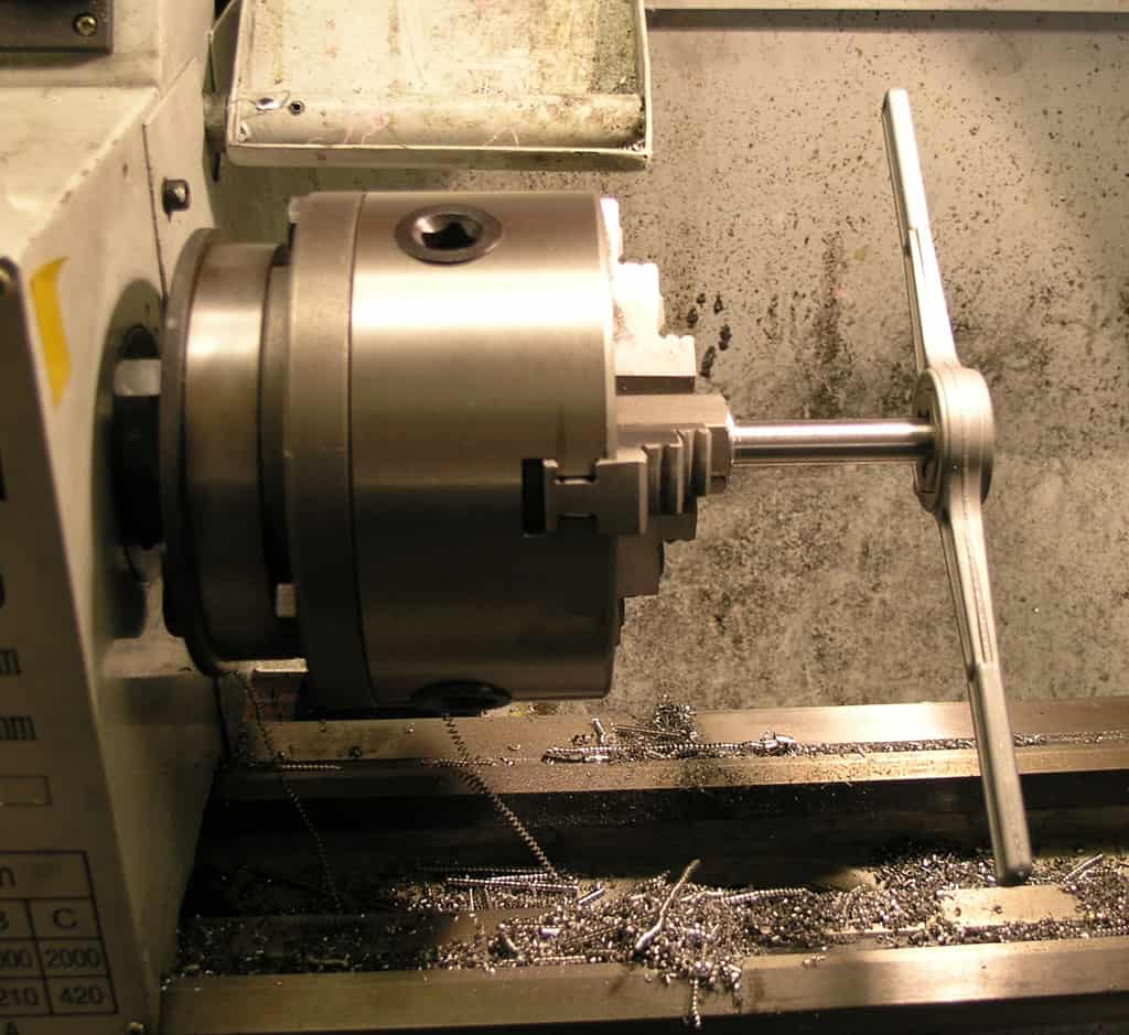 Metal lathe or turning center with workpiece on live spindle and surrounding tools and materials.