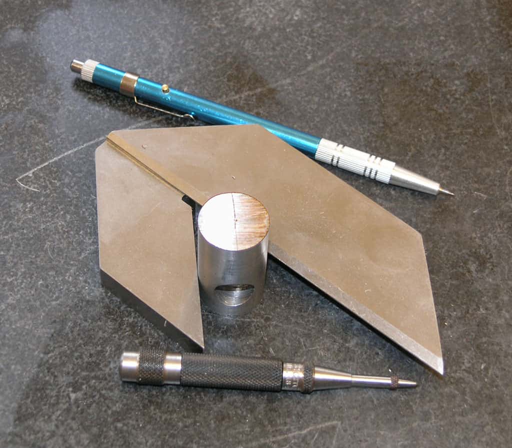 Precision tools including set square, calipers, and micrometer on dark gray surface.