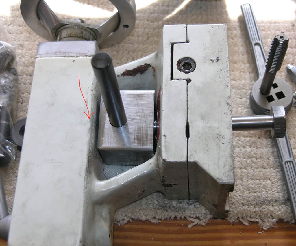 Metalworking tool on carpeted surface with rectangular base and vertical posts.