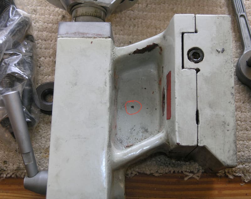 Worn white metal object with red highlighted central hole.