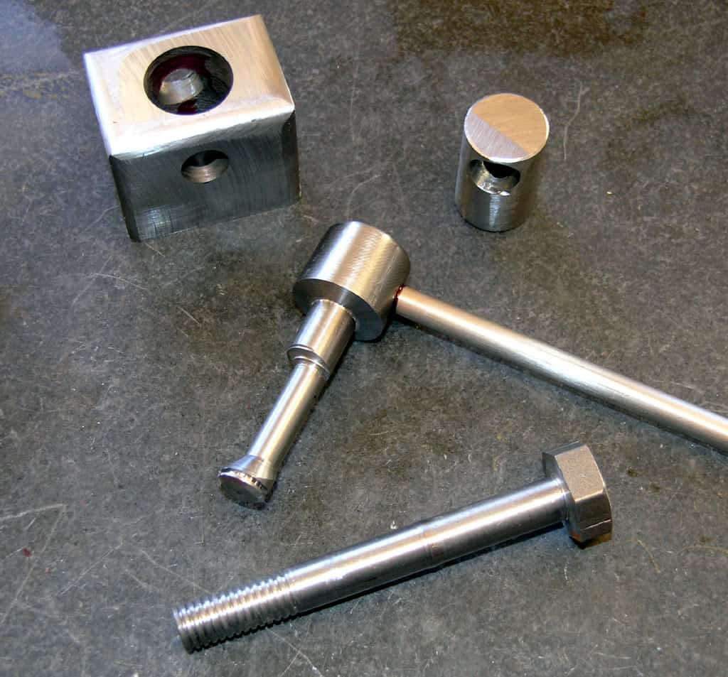 Metal parts, including bolts and nuts, on a dark surface.