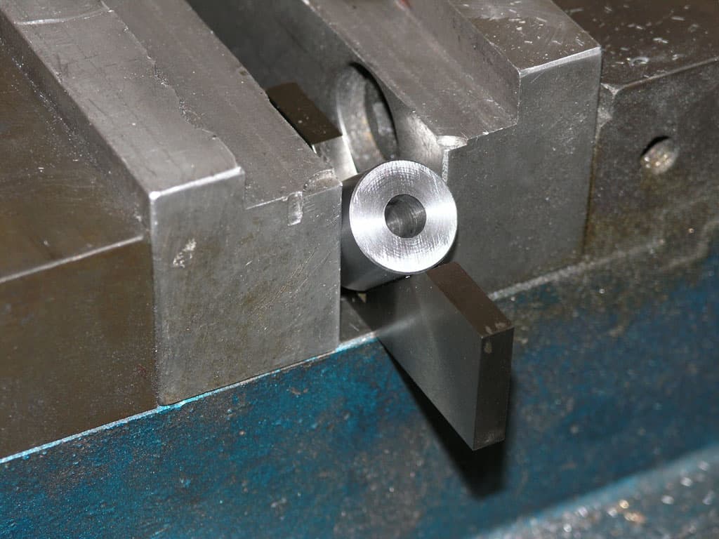 Metal object with circular hole in metal vice.