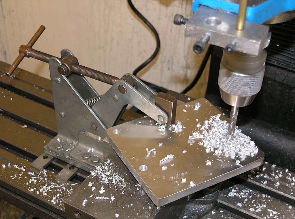 Metalworking vise attached to a workshop worktable with adjustable jaws and secure fasteners.