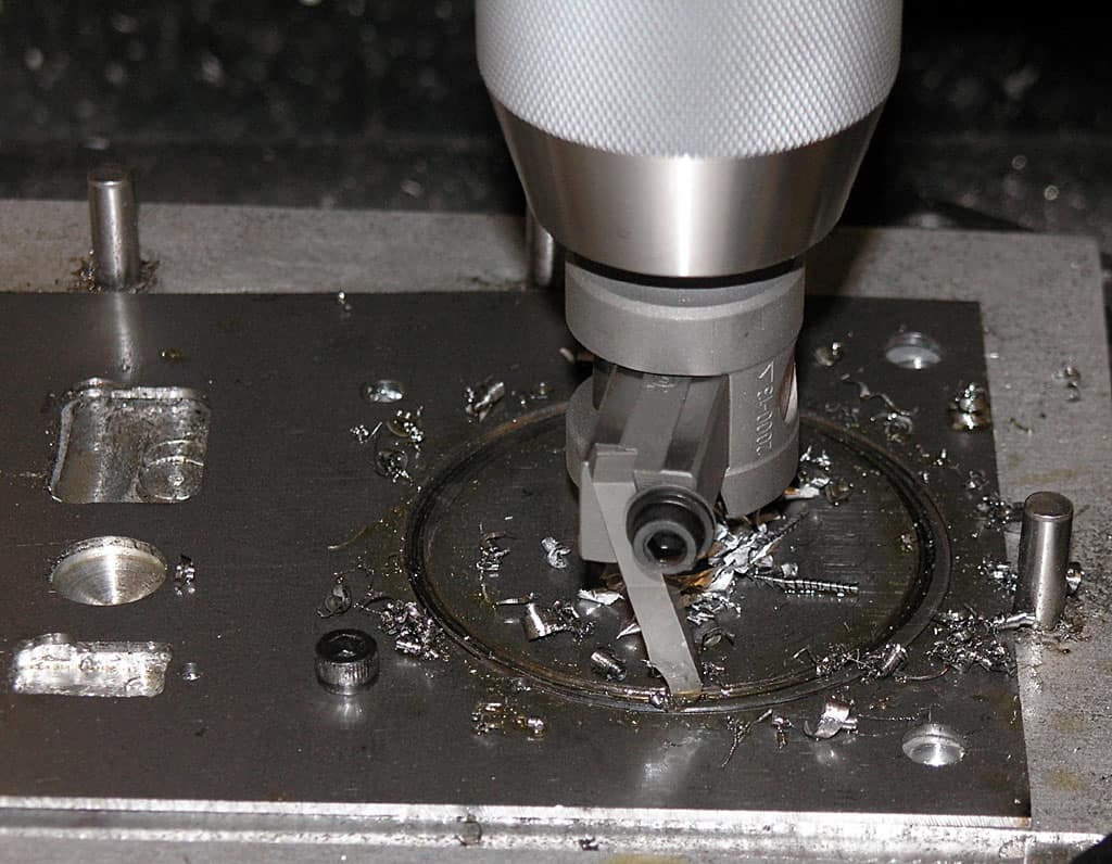 Close-up photograph of a drill press or milling machine, highlighting metal components and machinery parts.