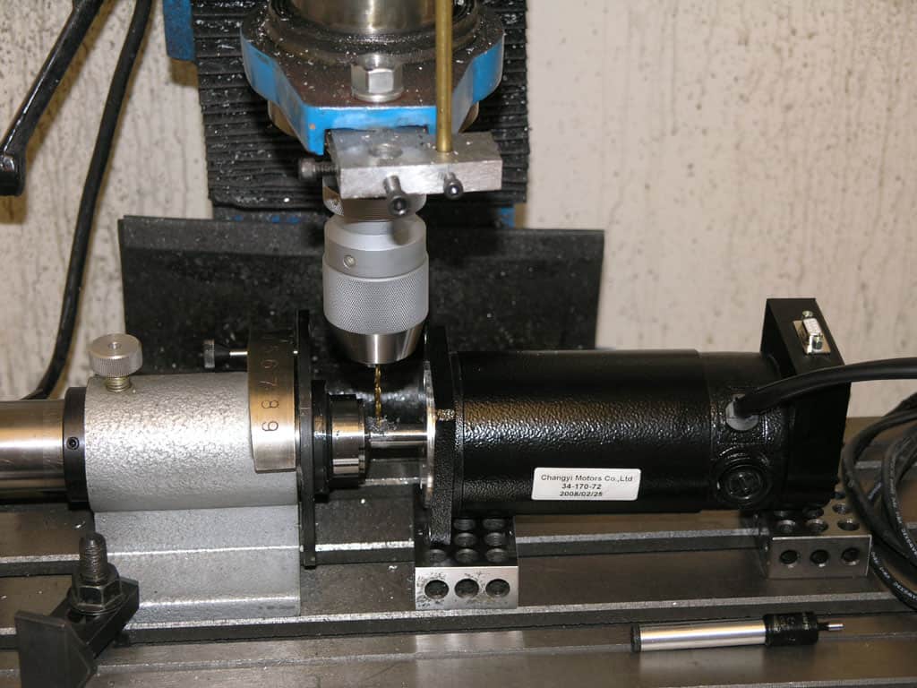 Metalworking lathe with black cylindrical attachment and cylindrical hole.