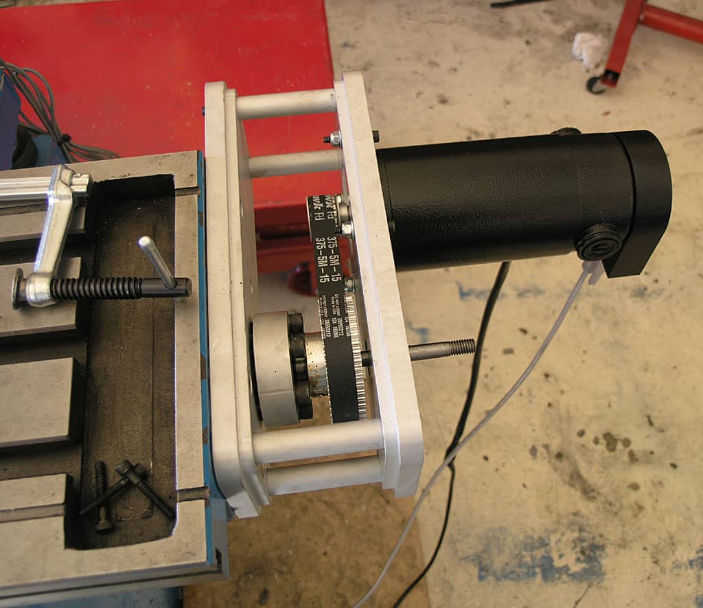 Cylindrical black machine tool with white text, situated within a metal frame on a concrete floor.