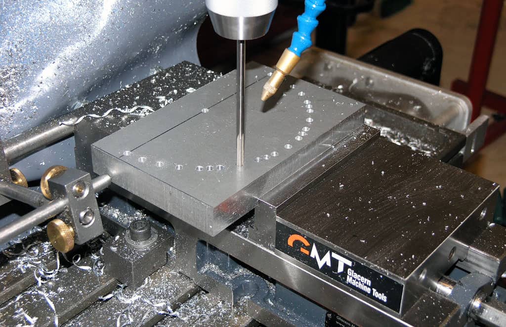 Metalworking machine in operation with GMT Glacern Machine Tools logo, surrounded by metal shavings and debris.