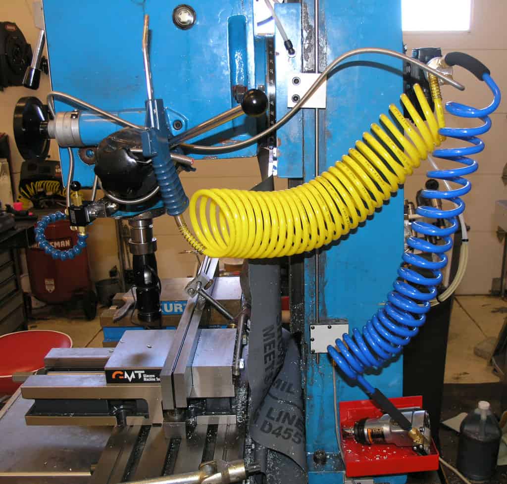 Blue metal workbench with tools and hose in a workshop setting.