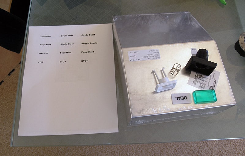 A person's hands resting on a glass table, with a piece of paper and machining terms written on it.