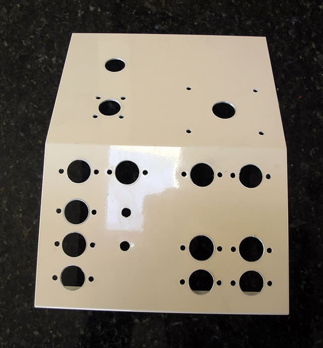 Beige metal plate with circular holes on a black granite countertop.