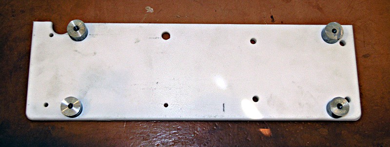 Metal plates with holes attached to a brown surface.