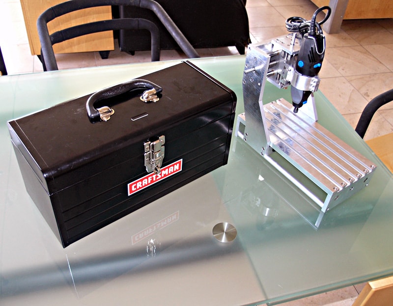 Black Craftsman toolbox with silver latches next to a small metal machine.