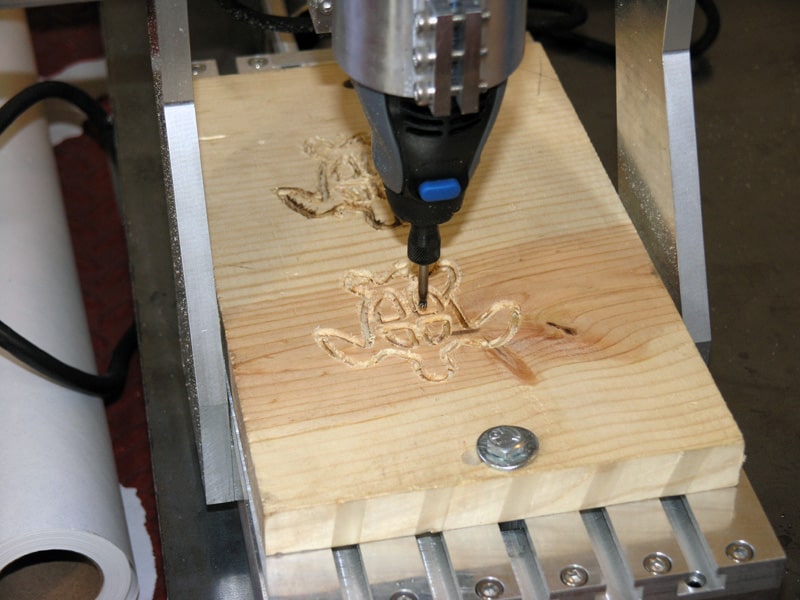 Wood carving machine in operation, metal base with wooden block.