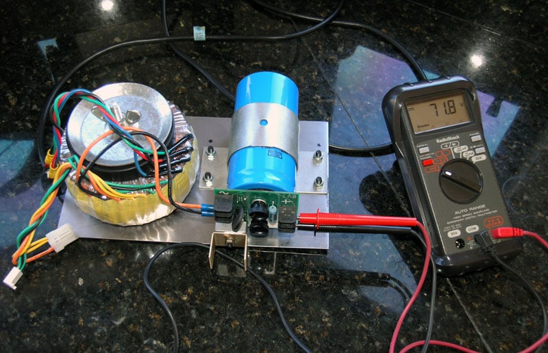 Electrical circuit on black granite countertop with multimeter reading 71.8 volts and various wires and components.