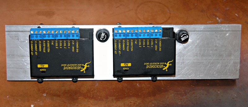Two black boxes with yellow text and blue circuit boards on a metal plate.