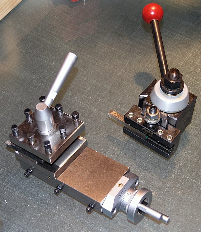 Two small machining tools with black bases and silver knobs on a dark gray tabletop.