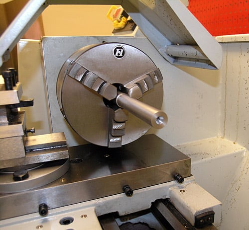 Metalworking lathe with cutting tool attached to headstock, made of steel, robust clamp system.