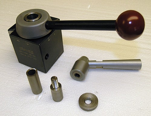 A black USMATIC box with a ball on a rod, next to two metal components.
