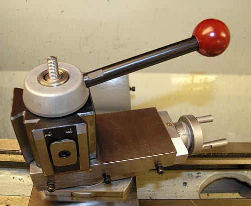 Metalworking tool with red ball on top, square base and adjustable arm.