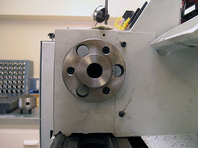 A metal component with a circular hole and four evenly spaced holes attached to a machine part.