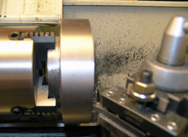 Metalworking lathe or milling machine in professional setting, precision machining task, metal piece being machined on spindle.