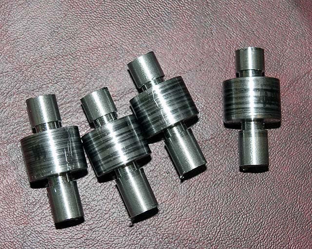 Cylindrical metal parts with threaded holes.