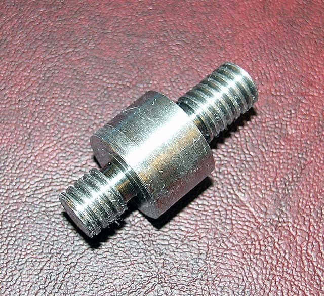 Uncoated stainless steel cylinder with threaded ends on a dark red leather background.