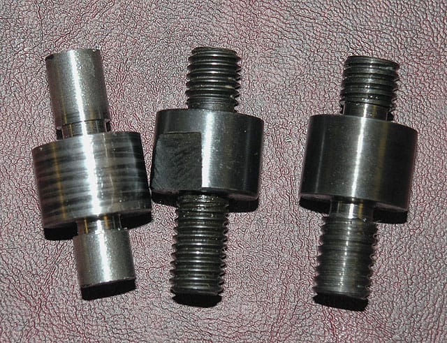 Machined metal parts with cylindrical shapes and threaded ends.