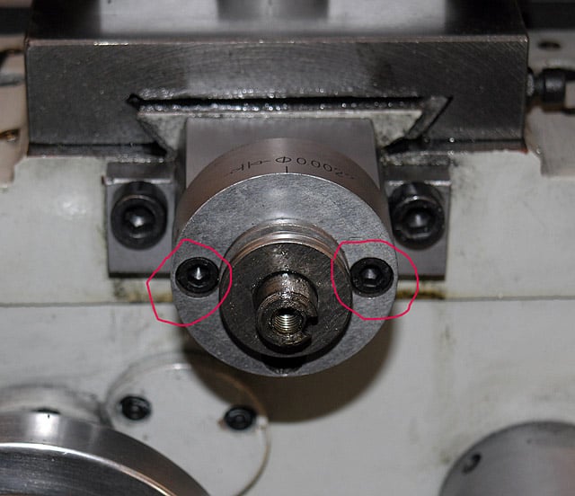 Metal component with two black screw heads and nuts.