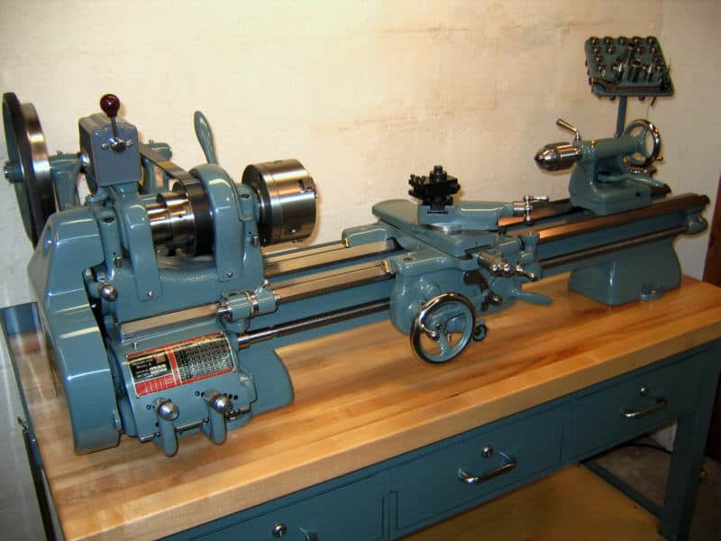 A blue lathe with a wooden table top and red sticker on a white background.