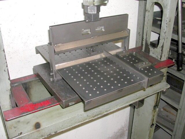 Metalworking press brake tooling setup with two rectangular metal plates and metal frame secured to a press brake machine.