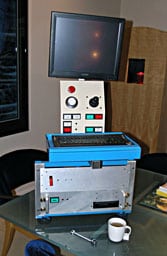 An old computer monitor on a metal box in front of a window, circa 1980s-90s.