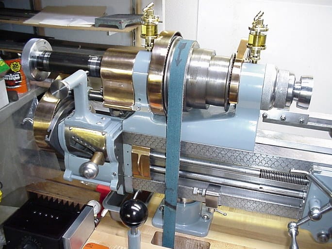 Industrial lathe with blue base and silver components in a factory workshop setting.