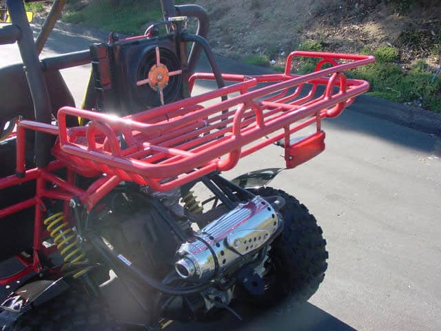 Red off-road vehicle with large wheel and suspension system in an outdoor setting.