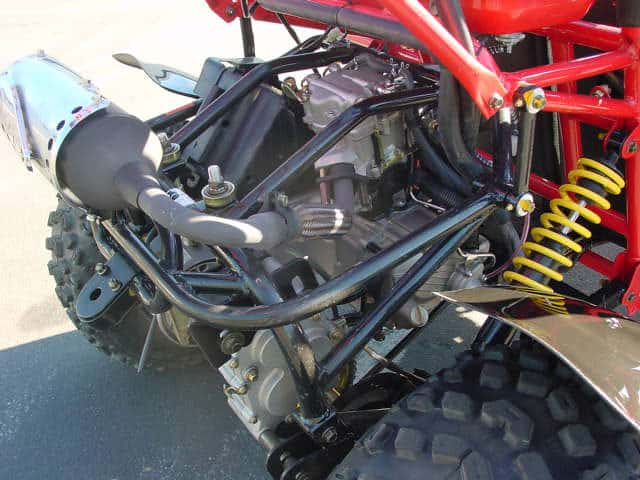A close-up view of an all-terrain vehicle's underside, showcasing its metal frame and suspension system.