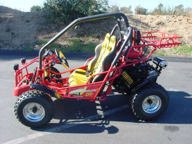 A red dune buggy parked on a path in front of a dirt hill.