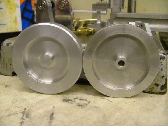 Two shiny silver metal circular objects on a workshop table.