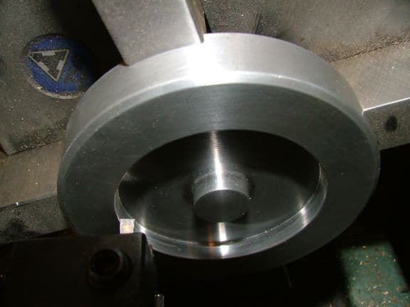 Silver metal ring with circular depression on dark background.