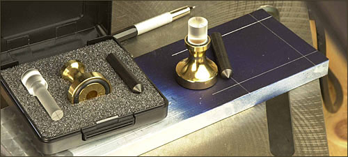 Brass center punch with white handle.