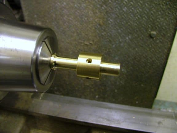 Brass end mill or drill bit with central hole and metal shank.