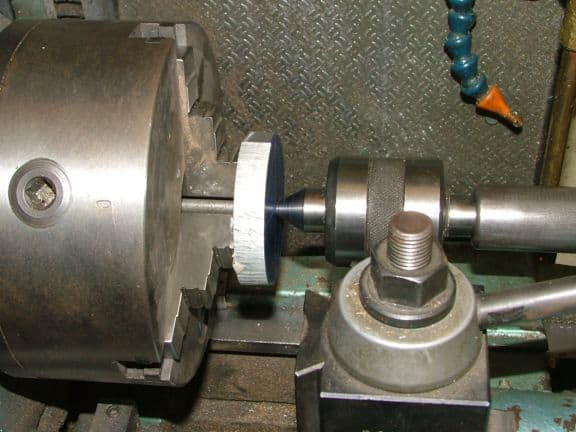 Metalworking lathe setup with cylindrical components and tools.