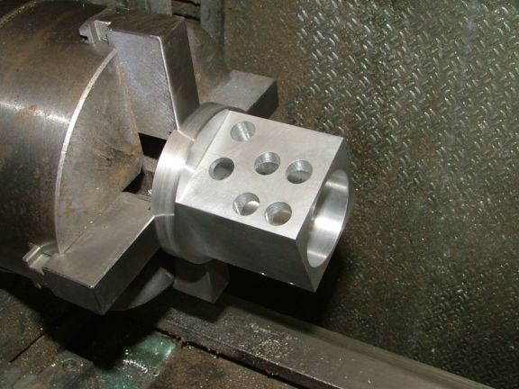 Metalworking lathe chuck with four evenly spaced holes in the end cap mounted on a machine tool.