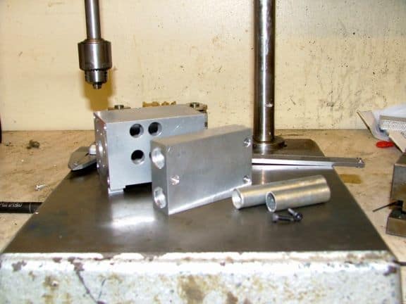 Metalworking press or vise on beige wall with cylindrical components.