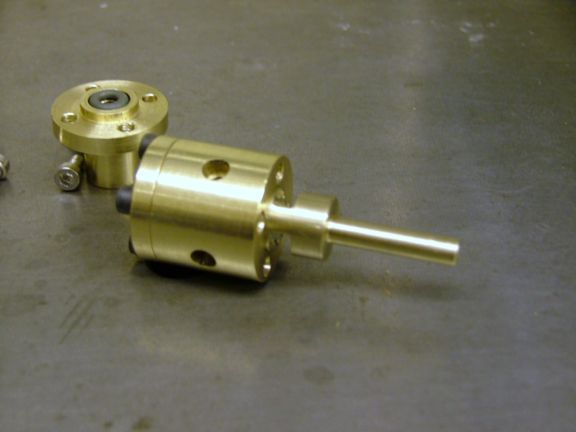 A shiny gold metal component with a cylindrical body and protruding rod.
