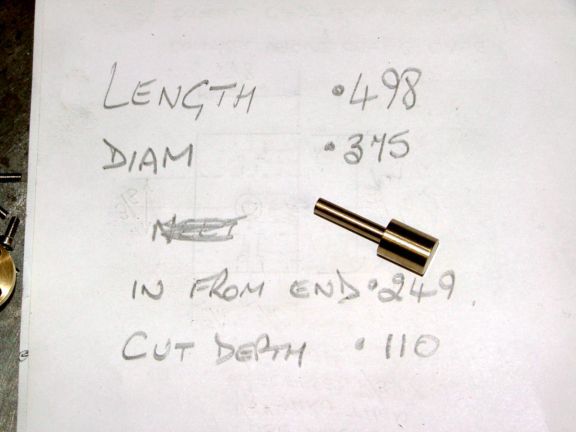 Handwritten note on white paper with measurements and small brass object.