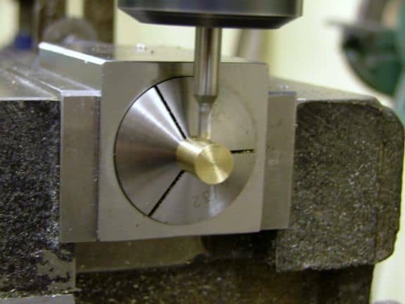 Dark gray metal vise with circular attachment and central hole on its side.